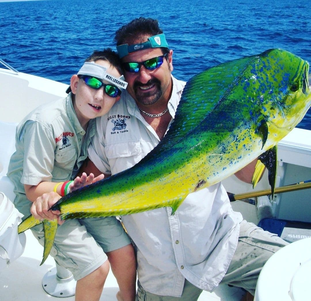 Young angler and Bruce holding a bull mahi on the boat